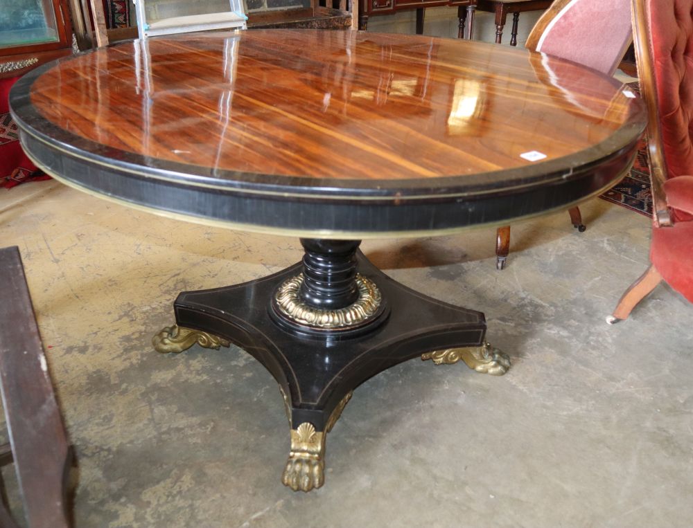 A George IV rosewood and ebonised gilt metal mounted circular breakfast table, on cast lion paws feet, diameter 121cm, H.74cm